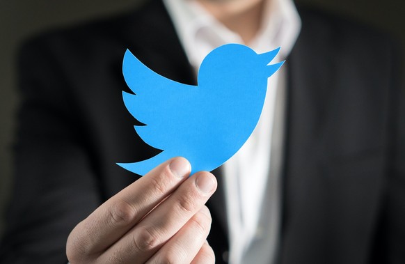 Mann hält Twitter-Logo in der Hand. (Symbolbild)