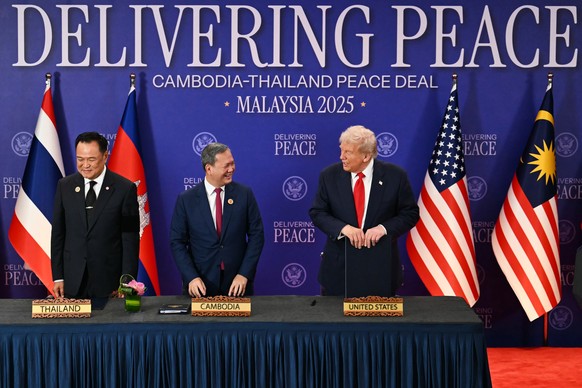 U.S. President Donald Trump talks to Cambodia&#039;s Prime Minister Hun Manet as Thailand&#039;s Prime Minister Anutin Charnvirakul, left, stands by after the ceremonial signing of a ceasefire agreeme ...