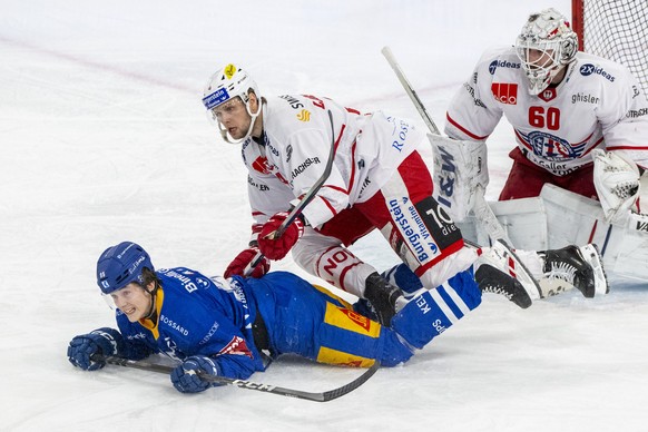 Colin Lindemann, links, von Zug im Spiel gegen Jacob Larsson, mitte, und Torhueter Melvin Nyffeler, rechts, von Rapperswil beim Eishockey Qualifikationsspiel der National League zwischen dem EV Zug un ...