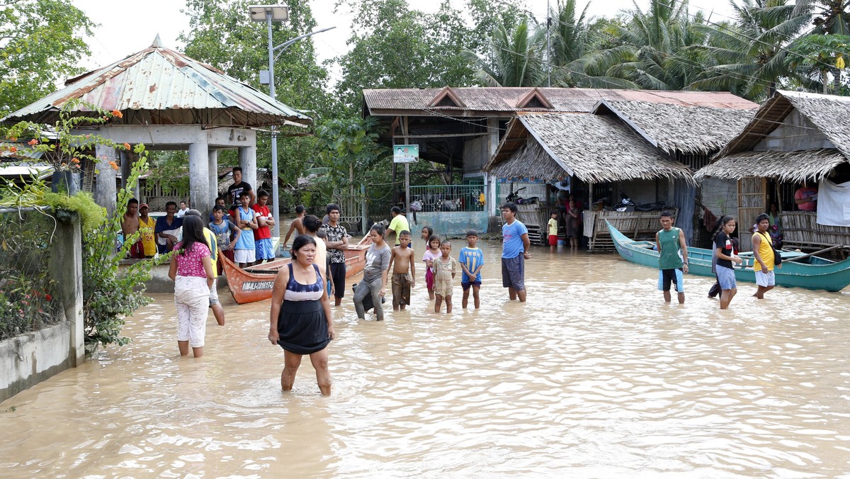 epa06403710 Filipino villagers wade on floodwater in flood hit town of Salvador, Lanao del Norte province, Philippines, 23 December 2017. According to news reports, Tropical storm Tembin brought mudsl ...