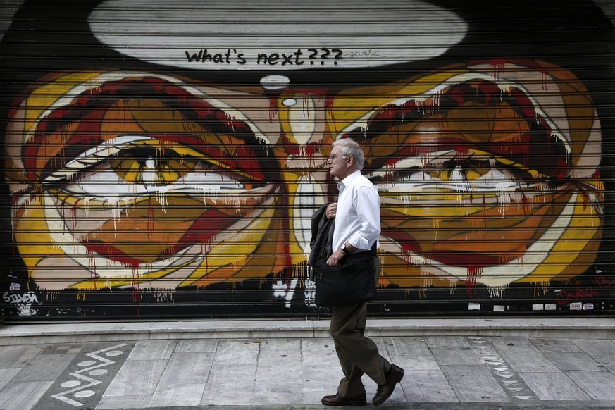 epa05981801 A man walks in front of a closed shop shutter covered with graffiti in central Athens, Greece, 22 May 2017. The issue of the Greek debt sustainability is expected to be put on the negotiat ...