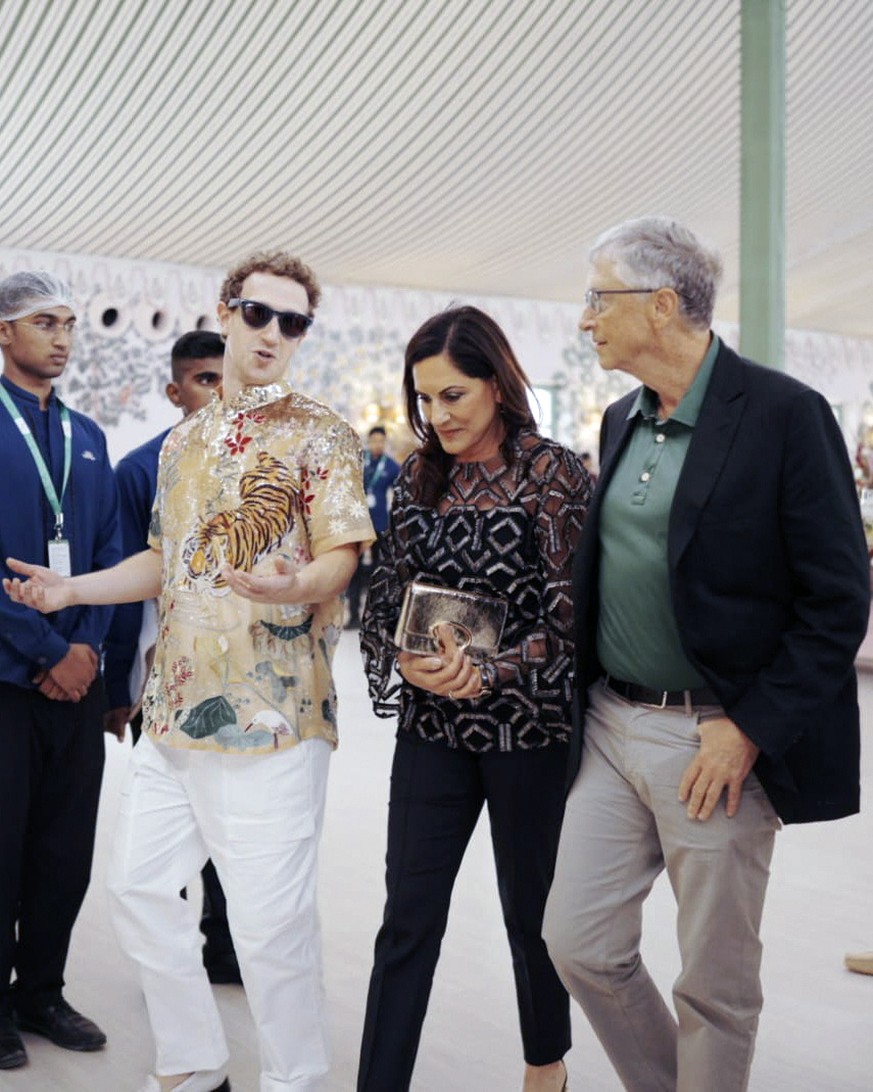 This photo released by the Reliance group shows Mark Zuckerberg making gestures while talking to Bill Gates, right, while walking with Paula Hurd, center, during a pre-wedding party of billionaire industrialist Muk...