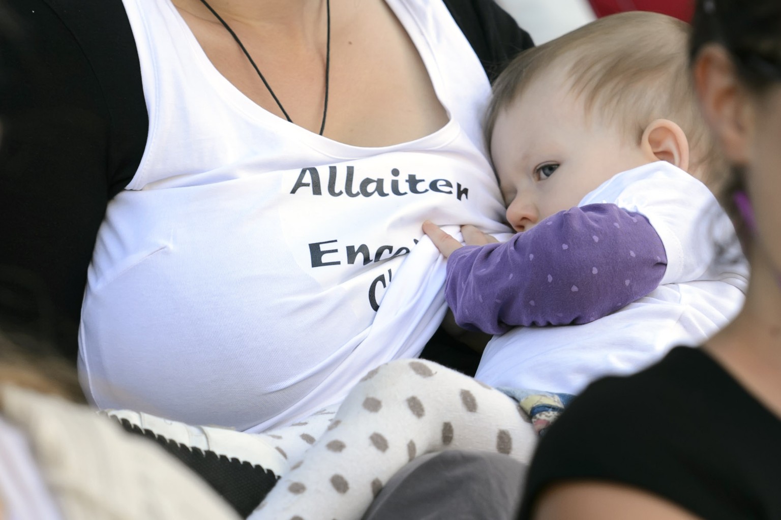 A mom nurses a baby during a flash mob protest to promote breastfeeding during the at the Place de la Riponne, in Lausanne, Saturday, September 13, 2014. 50 women gathered together and feed their baby ...