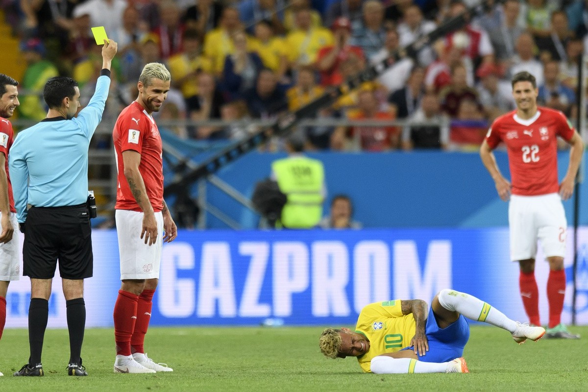 Switzerland's midfielder Valon Behrami, second left, reacts next to Brazil's forward Neymar, right, as Referee Cesar Ramos, left, gives a yellow card during the FIFA soccer World Cup 2018 gr ...