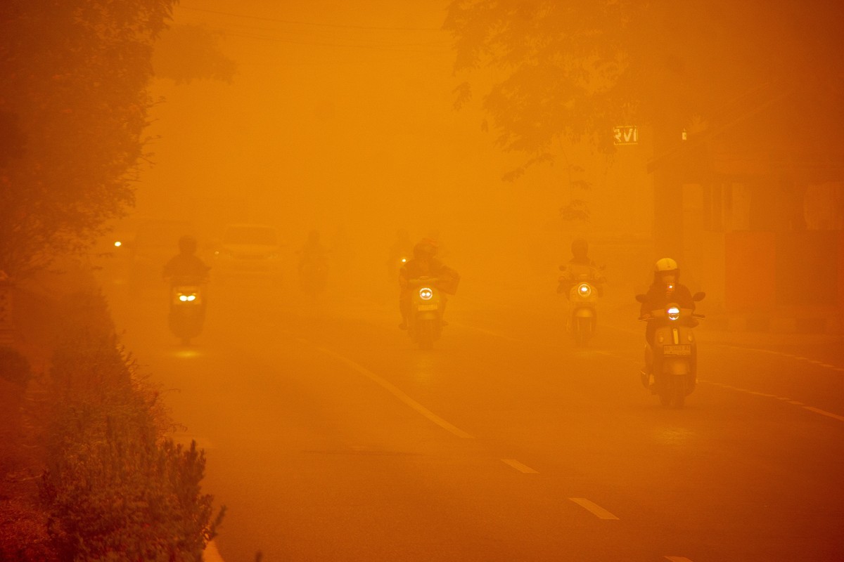 epa13303246 Motorists wearing protective face masks ride through thick wildfire haze in Palangkaraya, Central Kalimantan, Indonesia, 14 October 2026. Civil society groups in Borneo have filed a class- ...