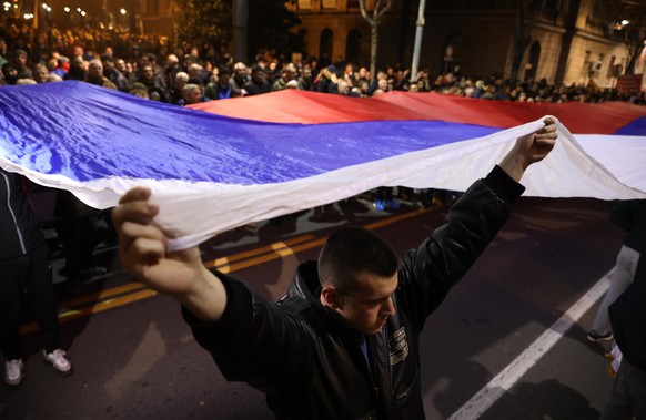epa10469221 Demonstrators carry a giant Serbian flag during a protest in Belgrade, Serbia, 15 February 2023. Hundreds of right wing nationalists have protested outside the Serbian presidency building  ...