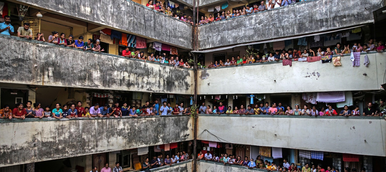 epa08313377 Indian people bang utensils and clap from the balconies of a residential building in Mumbai, India, 22 March 2020. Prime Minister Narendra Modi asks citizens to impose self-curfew to fight ...