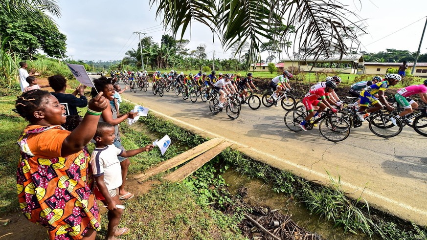 Das Fahrerfeld Peloton passiert das afrikanische Hinterland und wird dabei von vielen Zuschauern angefeuert - Landschaft - Landscape - Feature - Natur - Hintergrund - Illustration - Impression - Ueber ...