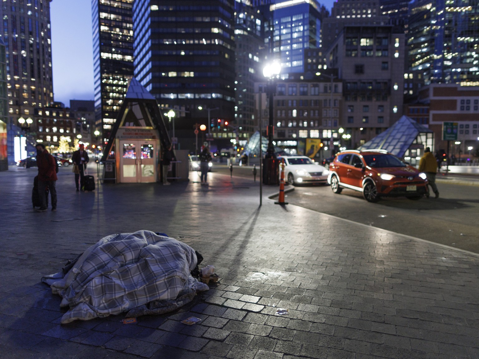 epa10446311 A person huddles under blankets on the sidewalk outside of South Station, despite the recent agreement for the building being kept open at night for sheltering from the cold by Governor Ma ...