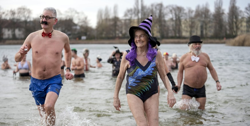 People with fancy hats and caps attend the annual New Year's swimming of the winter swimming club 'Seehunde Berlin', on New Year's Day at the Oranke Lake in Berlin, Germany, Wednes ...