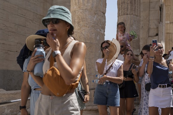 FILE - Tourists visit the ancient Acropolis hill during a heat wave in Athens, Greece, on July 21, 2023. Climate change is making heat waves crawl slower across the globe and last longer with higher t ...
