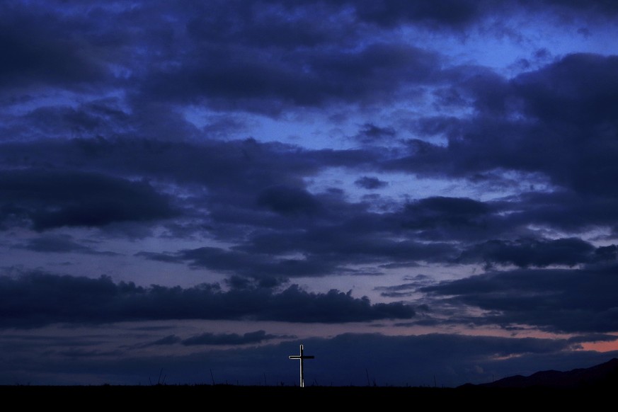 A partially illuminated cross sits above of 12th century monastery &quot;Panagia Chrisospiliotissa&quot; carved out of the side of a cliff in Deftera on the outskirts of Cyprus&#039; capital Nicosia,  ...