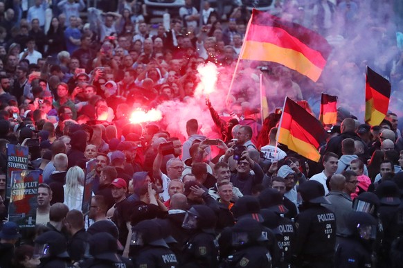 27.08.2018, Sachsen, Chemnitz: Demonstranten der rechten Szene zuenden Pyrotechnik und schwenken Deutschlandfahnen. Nach einem Streit war in der Nacht zu Sonntag in der Innenstadt ein 35-jaehriger Man ...