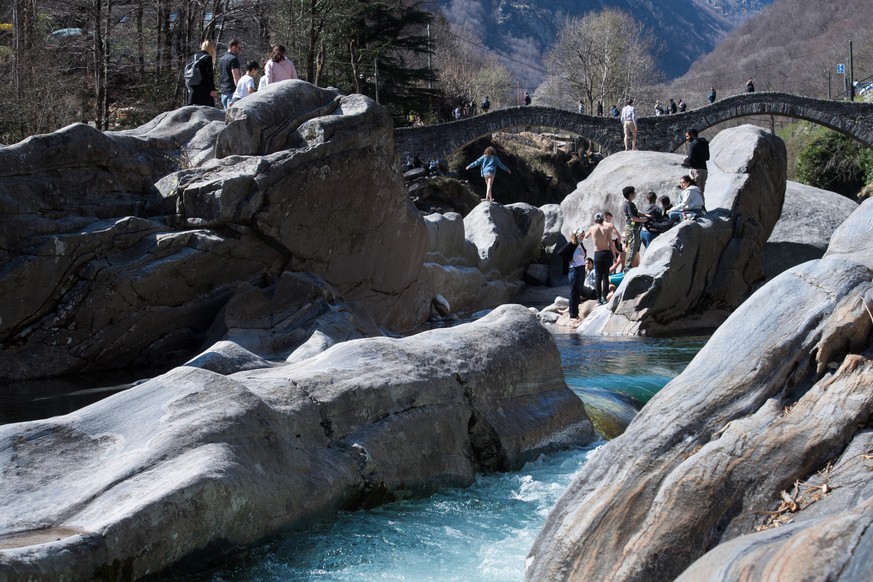 Osterausfluegler geniessen am Sonntag, 4. April 2021, trotz der Maskenpflicht im Freien das schoene Wetter am Ponte de Salti ueber den Fluss Verzasca bei Lavertezzo. Am Ponte dei Salti und den angrenz ...