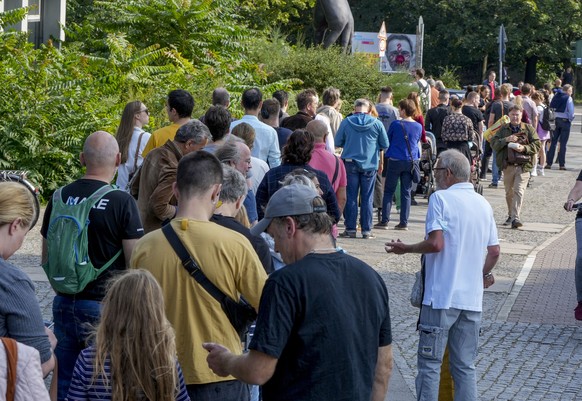 People queue in front of a polling station in the Moabit district of Berlin, Germany, Sunday, Sept. 26, 2021. German voters are choosing a new parliament in an election that will determine who succeed ...