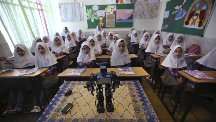 In this picture taken on Monday, Feb. 24, 2014, Veldan, a humanoid praying robot which is built by Iranian schoolteacher Akbar Rezaie, performs morning prayer in front of Alborz elementary school girl ...