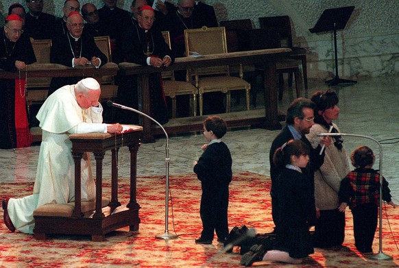 A young boy leaves his family deep in prayer, to look at Pope John Paul II as he recites the Holy Rosary in Latin before the faithful gathered in Pope Paul VI&#039;s Hall at the Vatican, during a Mass ...