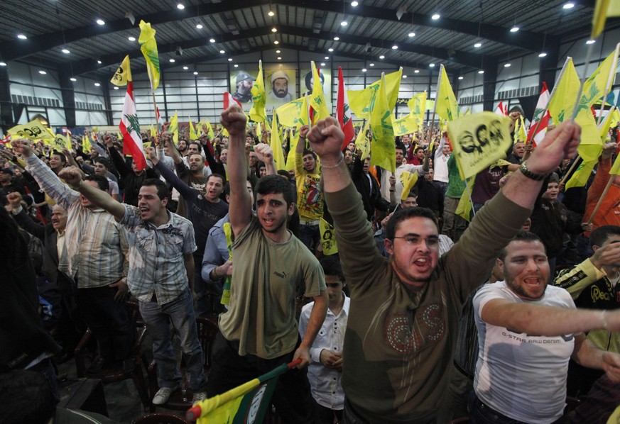 In this photo taken Tuesday, Feb. 16, 2010, Hezbollah supporters wave Lebanese and the party's flags during a rally commemorating the 2008 assassination of Hezbollah's top military commander ...