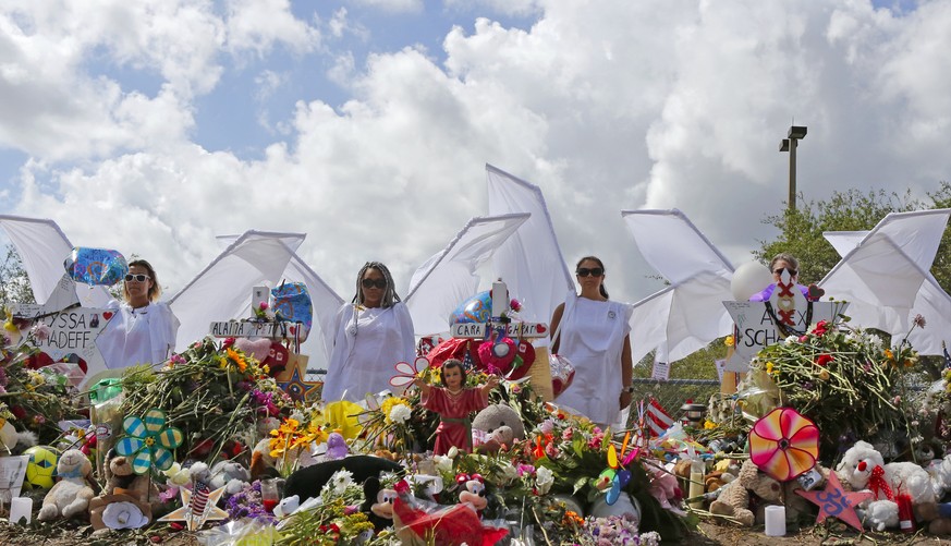 People dressed in white costumes as angels stand by a makeshift memorial outside Marjory Stoneman Douglas High School in Parkland, Fla., Sunday, Feb. 25, 2018. Thousands of students joined their paren ...