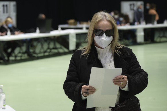 A woman wearing a face mask holds her ballot paper at a polling station for early voters in Portugal&#039;s general election, in Porto, Portugal, Sunday, Jan. 23, 2022. Those who registered for the ea ...