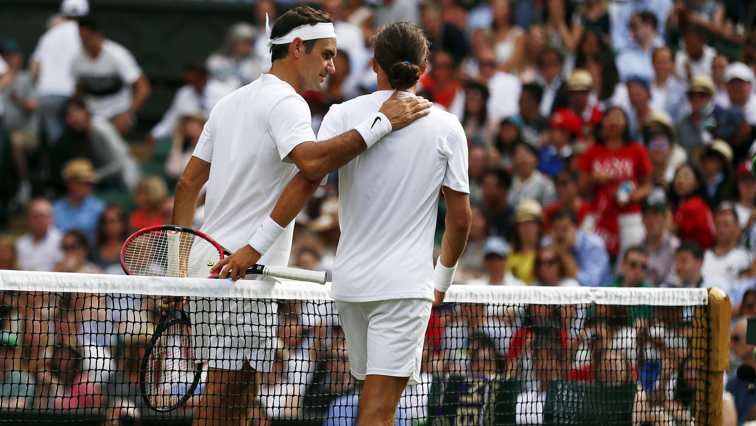 epa06065913 Roger Federer of Switzerland (L) at the net with Alexandr Dolgopolov of Ukraine who retired in their first round match during the Wimbledon Championships at the All England Lawn Tennis Clu ...