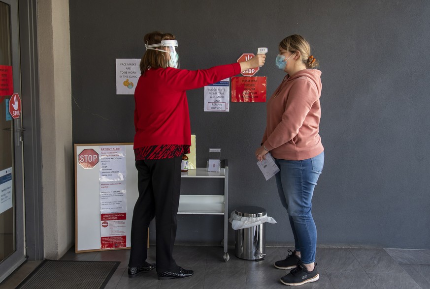 A patient has her temperature checked at a medical clinic during lockdown due to the continuing spread of the coronavirus in Melbourne, Thursday, Aug. 6, 2020. Victoria state, Australia's coronav ...