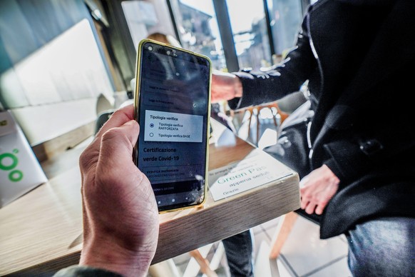 epa09625451 Staff of coffee bar checks the QR code confirming that people received the Covid-19 vaccine, in Milan, Italy, 06 December 2021. The measures on the &#039;enhanced&#039; green certificate ( ...