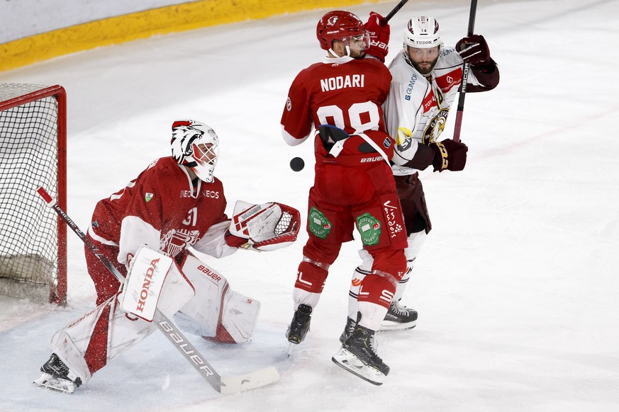 Lausanne&#039;s goaltender Sandro Zurkirchen, left, catches the puck past Lausanne&#039;s defender Matteo Nodari, center, and Geneve-Servette&#039;s forward Juraj Simek, right, during a National Leagu ...