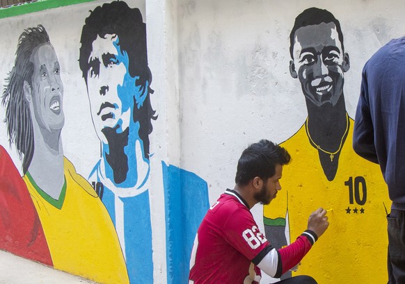 epa10308171 Bangladeshi artists working on a mural in a street in Dhaka, Bangladesh, 16 November 2022, showing famous soccer players as Mohamed Salah, Pele, Diego Armando Maradona, Ronaldinho, Cristia ...