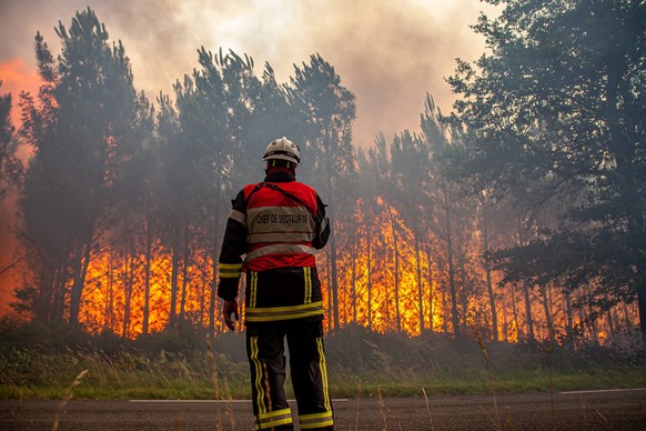 This photo provided by the fire brigade of the Gironde region (SDIS 33) shows a firefighter fighting a wildfire near Landiras, southwestern France, Saturday July 16, 2022 . Strong winds and hot, dry w ...