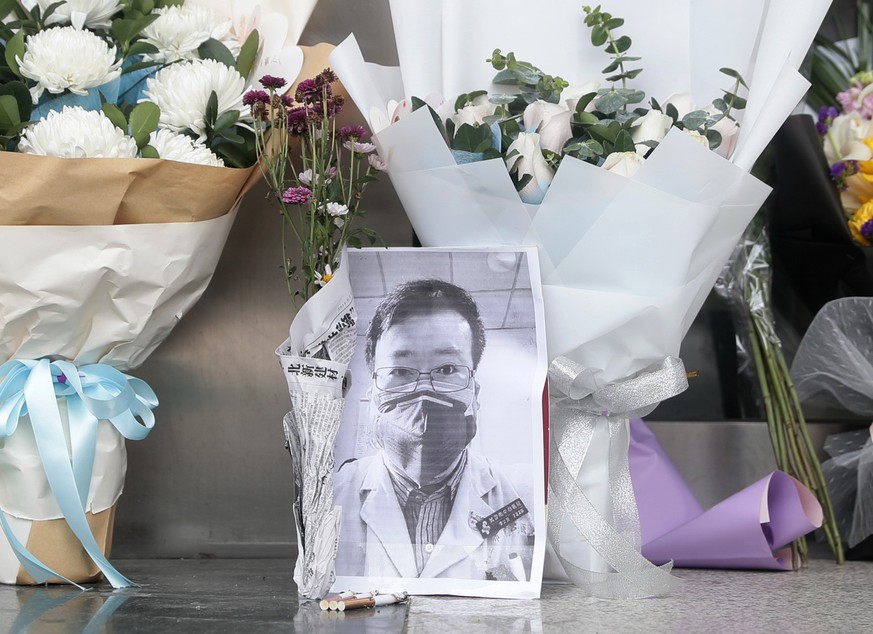 epa08199438 A picture of Dr. Li Wenliang, the Chinese whistle-blower who tried to sound the alarm on the coronavirus but was reprimanded by authorities, sits among offerings at a makeshift shrine outs ...