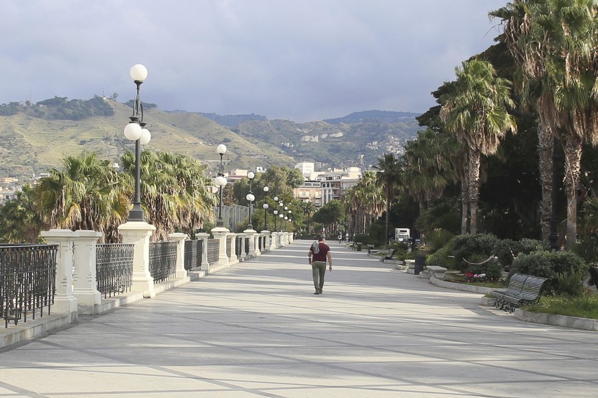 A man walks in Reggio Calabria, southern Italy, Friday, Nov. 6, 2020. The government placed four regions, including hard-hit Lombardy, into effective lockdown for two weeks because infections and hosp ...