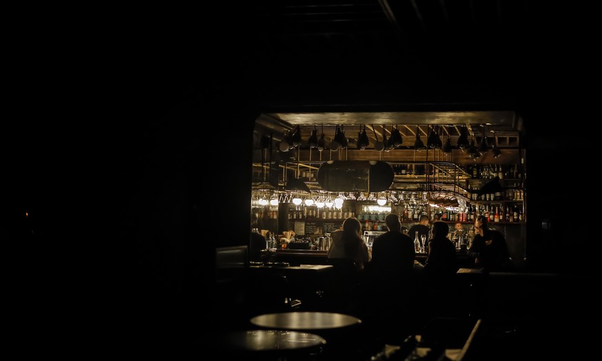 epa10267940 People sit inside a bar while the street lights are switched off in Dnipro, Ukraine, 26 October 2022. Scheduled power cuts were introduced in Kyiv, power operator Ukrenergo said, following ...