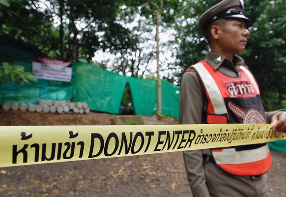 epa06873207 A Thai police officer stands guard at the blocking area during the &#039;D-Day&#039; for the ongoing rescue operation for the child soccer team and their assistant coach to exit the cave a ...