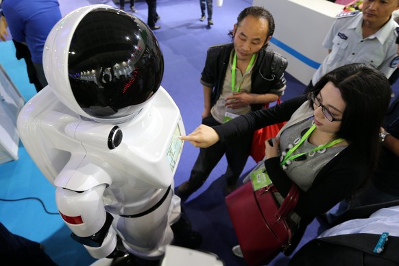 epa04745737 A visitor touches a robot on display at the 18th China Beijing International High-Tech Expo in Beijing, China, 13 May 2015. The expo runs from 13 to 17 May at the China International Exhib ...