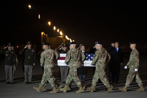 President Donald Trump looks on as a U.S. Army carry team moves a transfer case containing the remains of Chief Warrant Officer 2 Kirk T. Fuchigami Jr., of Keaau, Hawaii, who according to the Departme ...