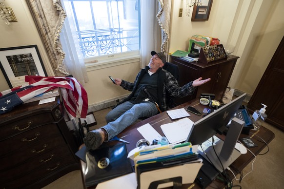 epaselect epa08923440 A supporter of US President Donald J. Trump sits on the desk of US House Speaker Nancy Pelosi, after supporters of US President Donald J. Trump breached the US Capitol security i ...