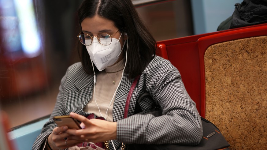 FILE - A woman wearing an FFP2 face mask looks at her phone on a subway train in Lisbon, Thursday, Jan. 6, 2022. Italy, Spain and other European countries are re-instating or stiffening mask mandates  ...