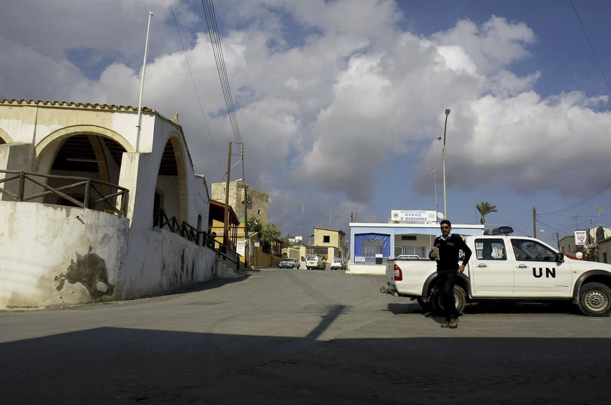FILE - A UN police officer walks in front of a UN vehicle at the square of Pyla village at the UN buffer zone, outskirt of coastal city of Larnaca, Cyprus, Thursday, Jan. 8, 2009. Three United Nations ...