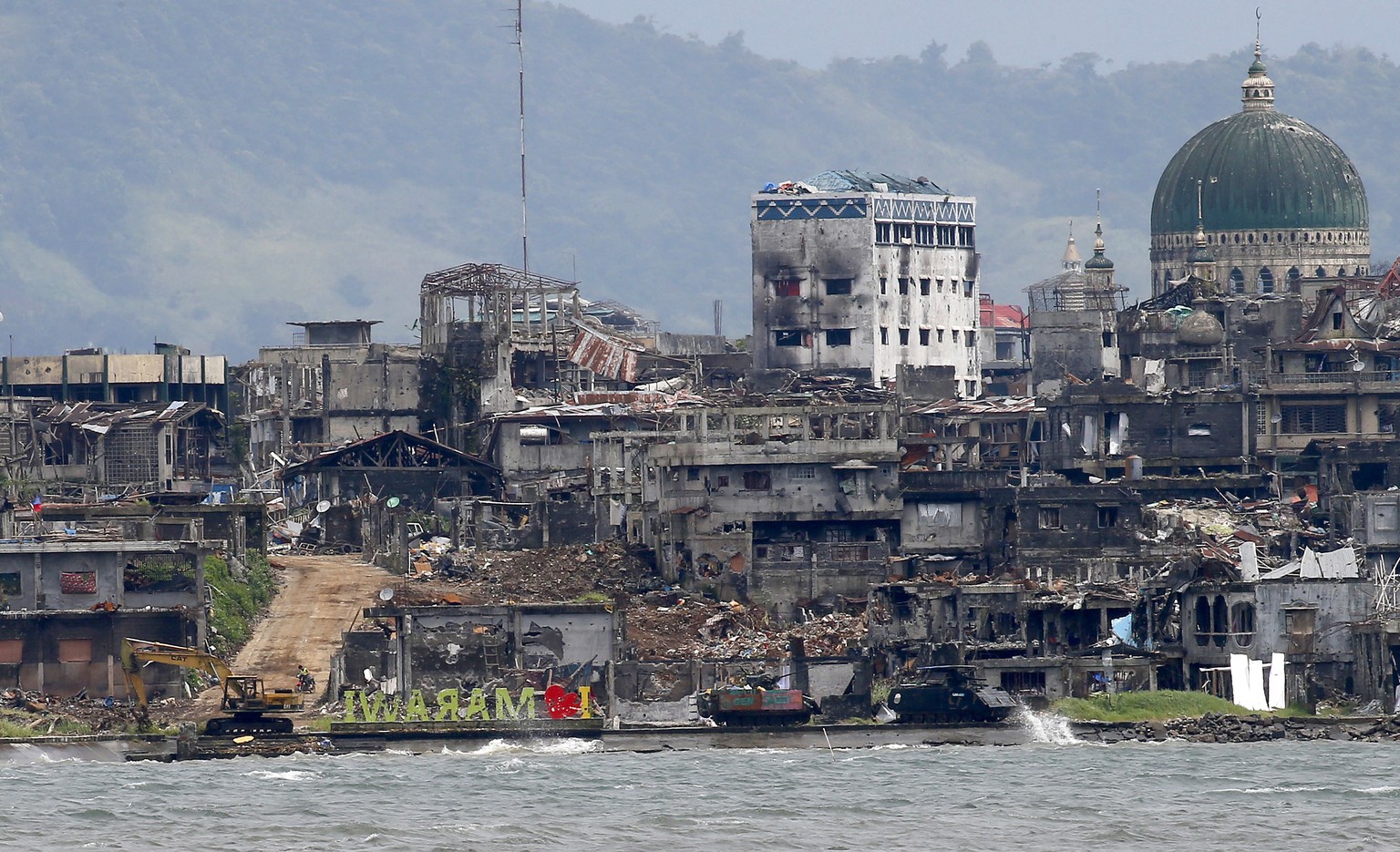 Armored Personnel Carriers are positioned near the bullet-riddled &quot;I Love Marawi&quot; landmark sign, center, at the &quot;Main Battle Area&quot; where pro-Islamic group militants are making a fi ...