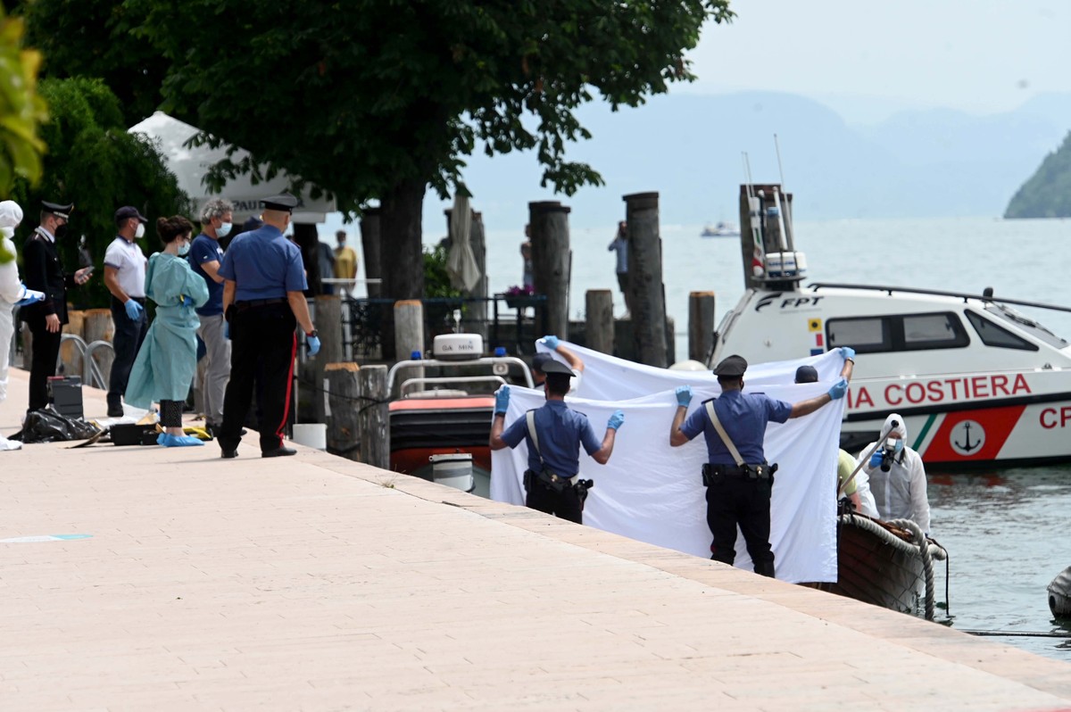 Italian police hold up a white sheet as forensic police inspect a boat as they investigate two German tourists from Munich for a boat collision which killed an Italian man and woman, in Salo', on ...