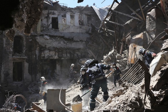Donetsk People Republic Emergency Situations Ministry employees clear rubble at the side of the damaged Mariupol theater in Mariupol, in a territory under the government of the Donetsk People's Republic, eastern Ukraine, Thursday, May 12, 2022. (AP Photo)