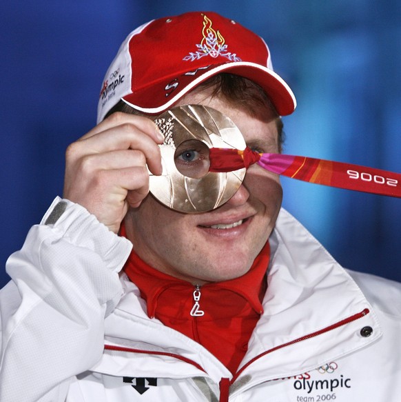 Swiss Ambrosi Hoffmann looks through the Bronze medal he won in today's Alpine Skiing Super-G race in the mixed zone of the medal ceremony in Turin, Italy, Saturday, February 18, 2006, during the ...