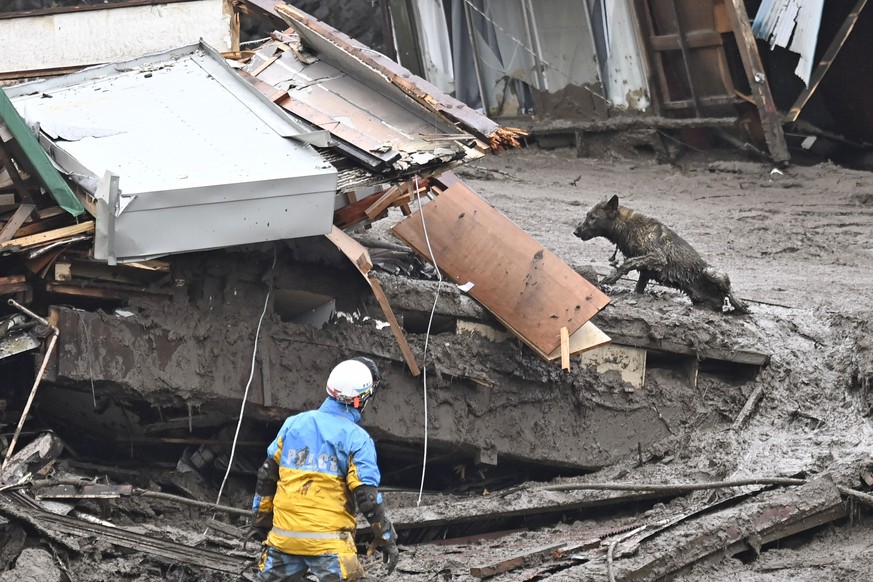 A rescuer conducts a search operation with sniffer dog at the site of a mudslide at Izusan in Atami, Shizuoka prefecture, southwest of Tokyo, Sunday, July 4, 2021. More than 1,000 soldiers, firefighte ...