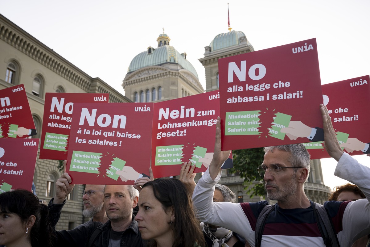 Sympathisanten posieren mit Plakaten vor dem Bundeshaus waehrend der Fotoaktion der Gewerkschaft Unia zur Nationalratsdebatte ueber die Allgemeinverbindlicherklaerung von Gesamtarbeitsvertraegen (GAV) ...