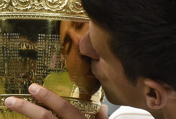 epaselect epa04844369 Novak Djokovic of Serbia kisses the championship trophy after beating Roger Federer of Switzerland in the men&#039;s final of the Wimbledon Championships at the All England Lawn  ...