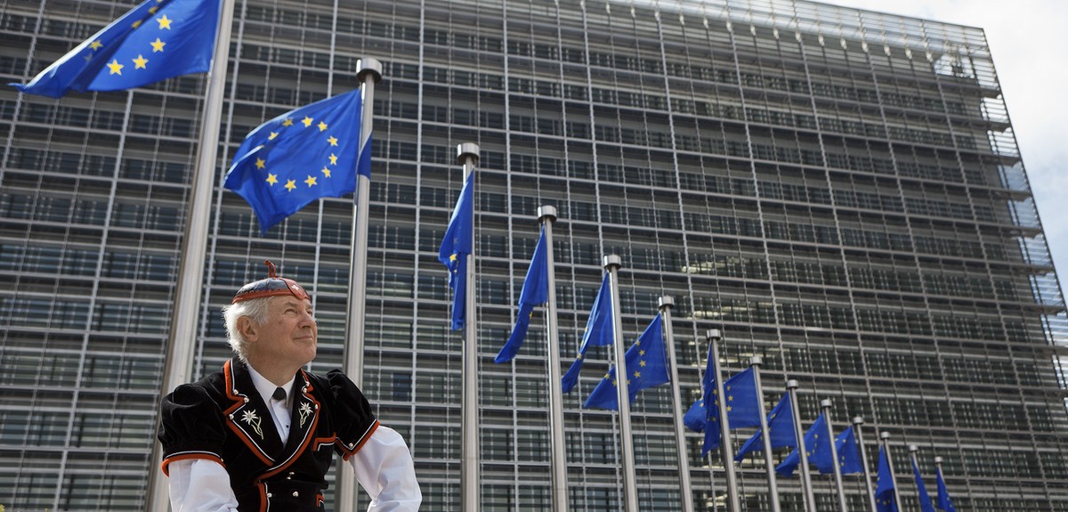 Flags of the European Union wave in front of the European Commission building in Brussels, June 8, 2011, while "Mister Swiss", dressed in a traditional Swiss costume, looks on. He is on his  ...