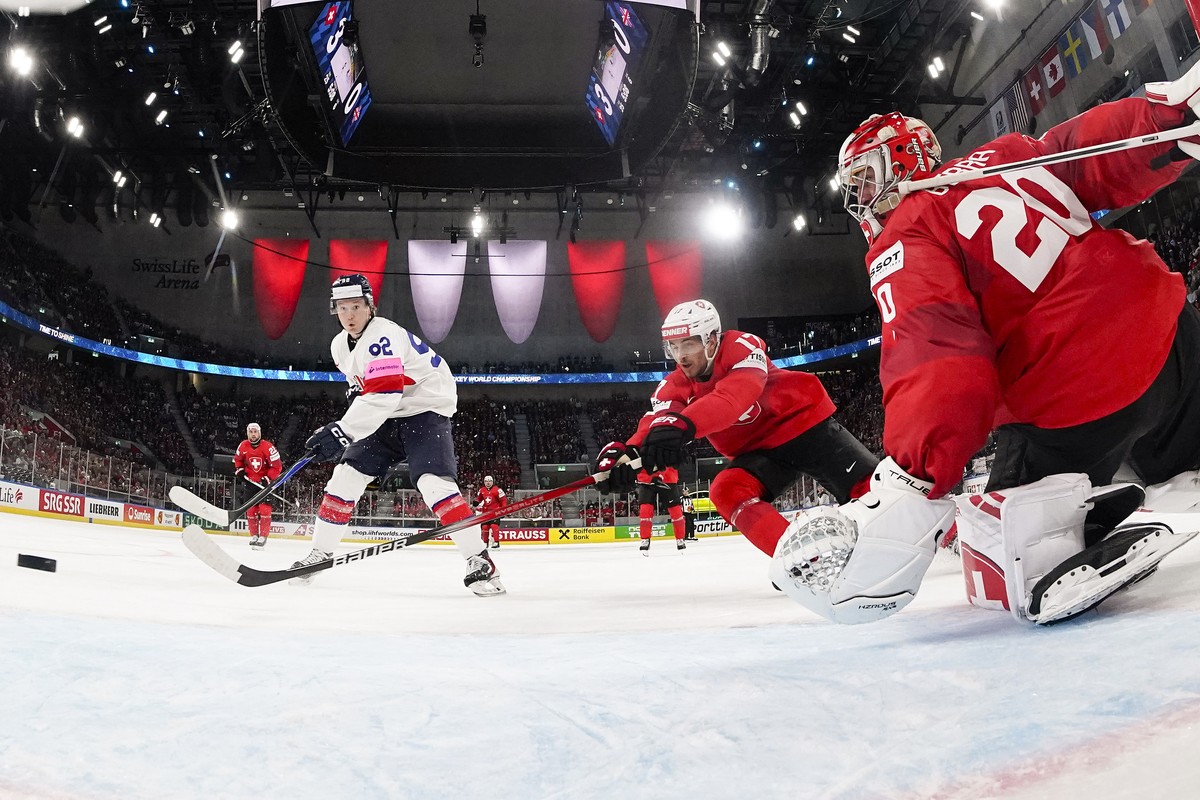 Great Britain's Josh Waller, left, scores to 3-1 against Switzerland's Ken Jager, center, and Switzerland's goaltender Reto Berra, during the 2026 IIHF Men's Ice Hockey World Champ ...