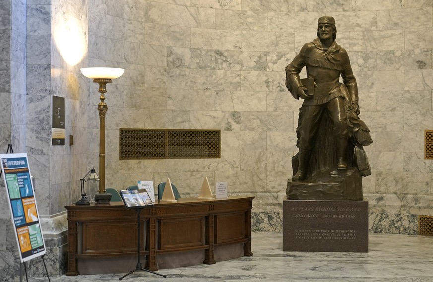 A statue of Marcus Whitman stands next to a visitors&#039; information desk in the Legislative Building at the Capitol in Olympia, Wash., Wednesday, May 12, 2021. For generations, Whitman has been vie ...