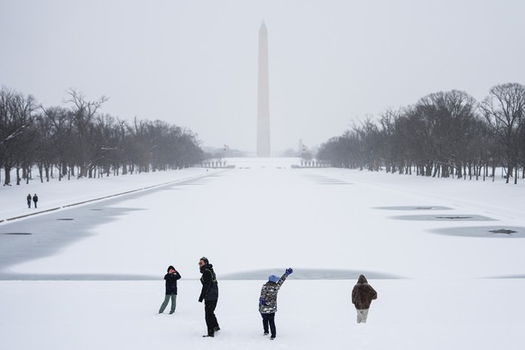 People walk along the National Mall as snow falls, Sunday, Jan. 25, 2026, in Washington. (AP Photo/Julia Demaree Nikhinson)